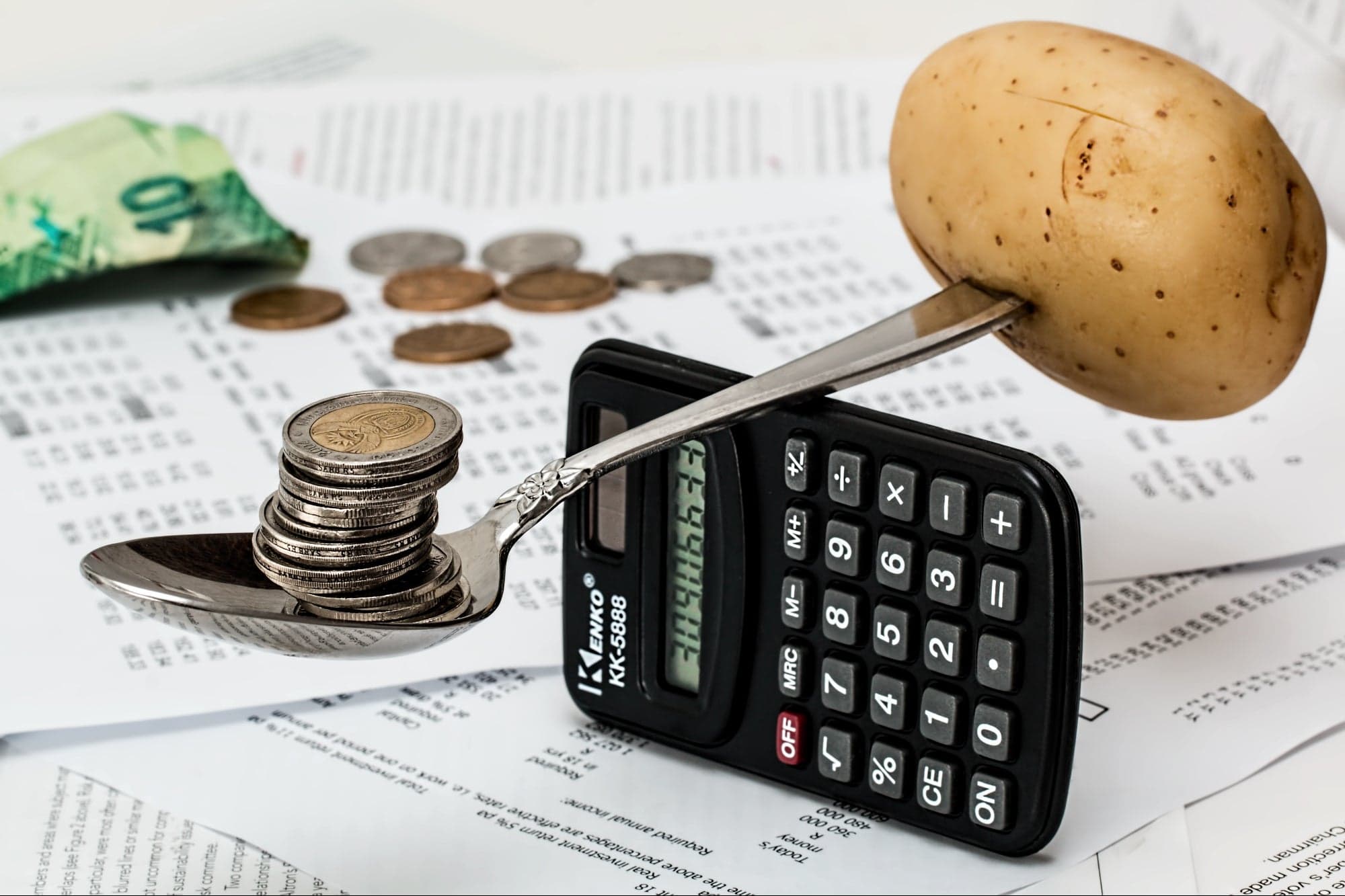 سیب زمینی و سکه روی دو طرف قاشق غذاخوری روی ماشین حساب