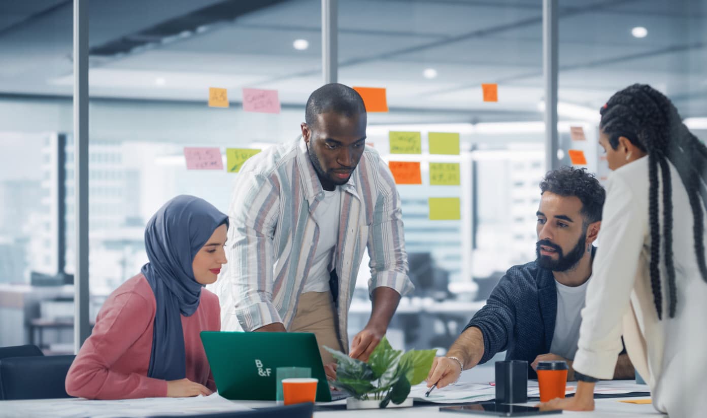 مدیر پروژه و کارکنان دور میز در اتاق شیشه‌ای جلسات